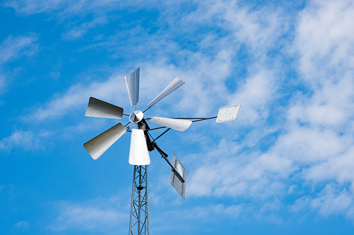 Wind generator with solar panels on the background of the sky, space for text.