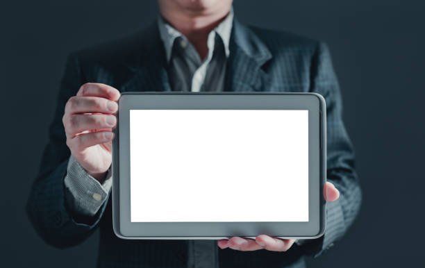 istock businessman in suit stand showing a tablet white screen display for mockup content. 1621014442