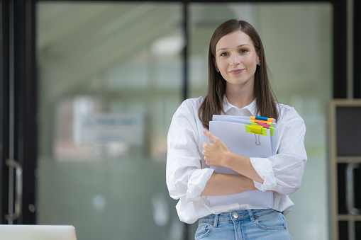 Smiling businesswoman holding a pile of paperwork.