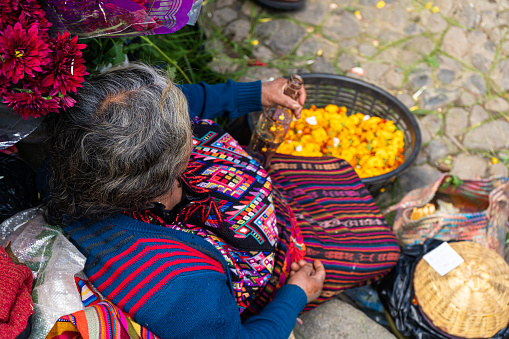Chichicastenango Guatemala - October 10, 2019:  A Mayan woman is offering her flower petals in the market.