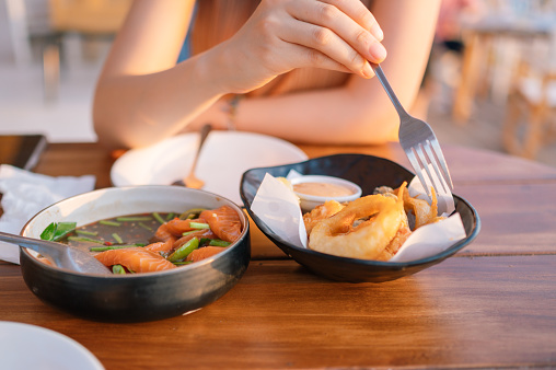Closeup women eating fish and chip salmon fusion thai doof on beach restaurant