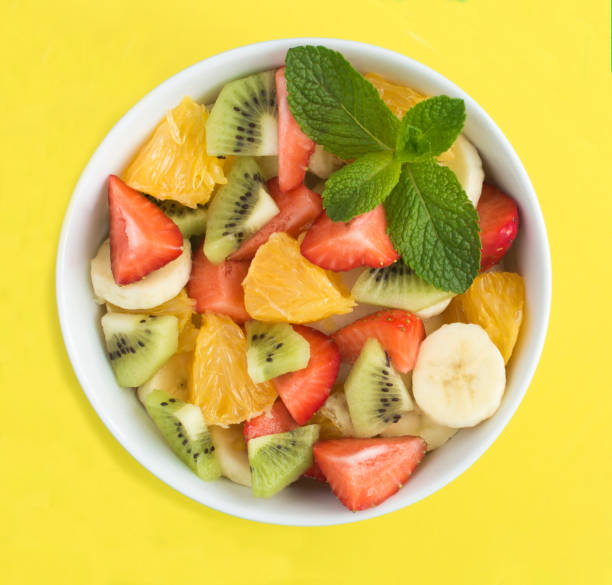 istock Fruit salad in the white bowl on the yellow background. Top view. Close-up. 1621034992