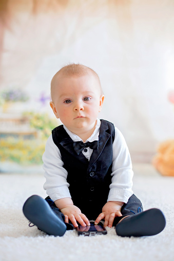 Cute little toddler boy, dressed smart casual, playing with little black and white rabbit at home