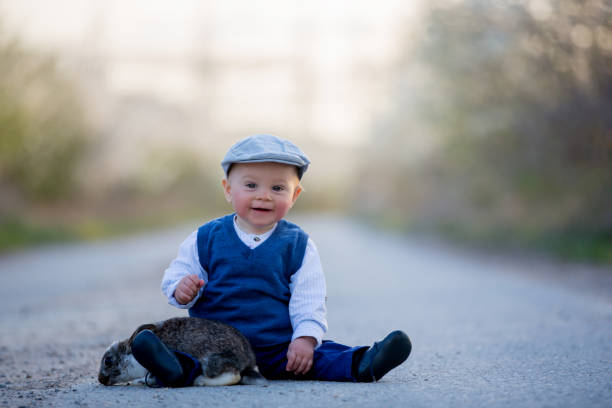 愛らしい幼児男の子、咲く木と田舎道でウサギと遊ぶ子供 - single lane road footpath flower formal garden ストックフォトと画像