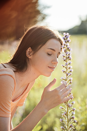 Pollen season. Summer allergies are caused by pollen from grass and Flowers. Young woman smells the blooming Flowers. Pollen and molds Causes Summer Allergies.
