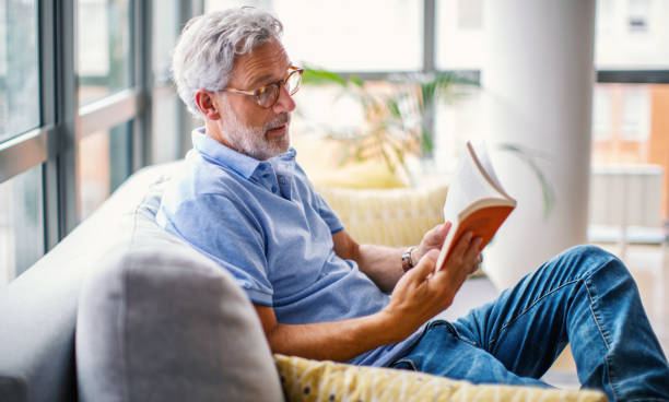 istock Mature man reading a book on the sofa. 1621054551