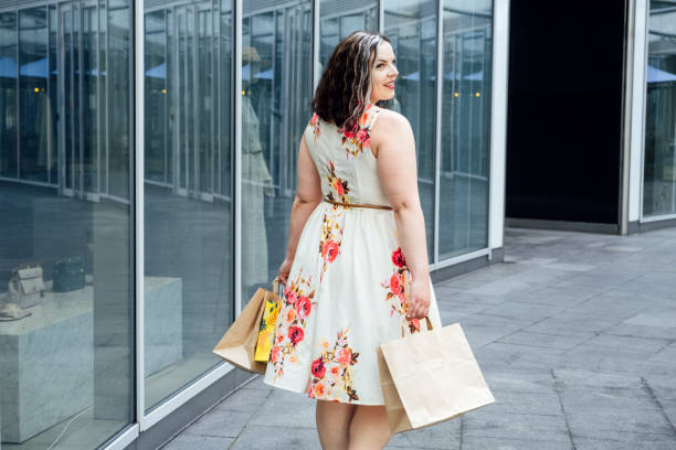How to Shop for Summer Fashion on a Budget. Choosing the Right Fabrics for Hot and Humid Summer Weather. Outdoor portrait of stylish curvy woman with shopping bags How to Shop for Summer Fashion on a Budget. Choosing the Right Fabrics for Hot and Humid Summer Weather. Outdoor portrait of stylish curvy woman with shopping bags. plus size woman fashion laughing stock pictures, royalty-free photos & images