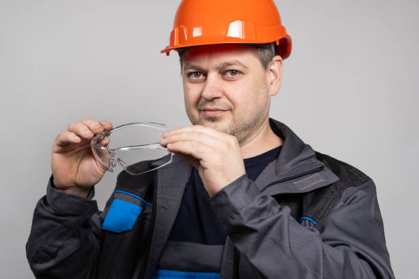 istock A construction worker in a helmet and overalls put on goggles protective glasses on a white background. 1621078872