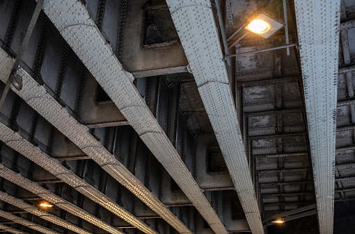 Steel girders with rivets underneath a railway bridge. Seen on Southwark Street in London, UK.