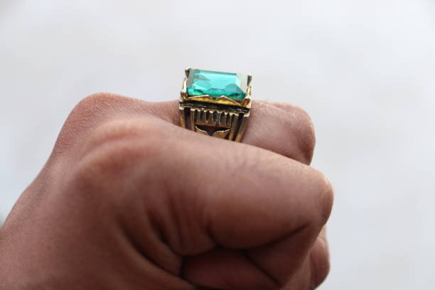 istock An Ancient Golden Ring embedded with Green Emerald Stone Gem worn by an Indian man in the Middle finger making feast in an isolated White Background 1621094651