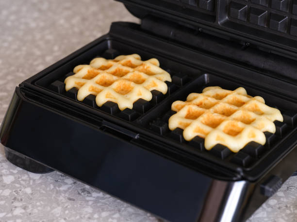 istock A waffle maker with two gluten-free homemade waffles inside of it standing on kitchen countertop. 1621117103