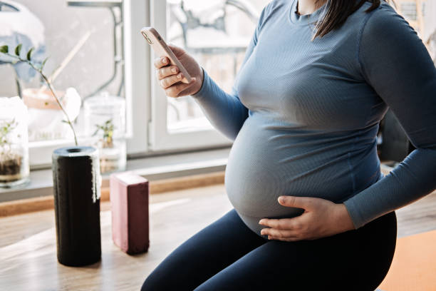 istock Pregnancy Workout Apps, Pregnancy Exercise Apps. Prenatal and Postnatal Workout, Pregnancy Wellness and Yoga Workouts in cell phone. Pregnant woman looking for Workout in phone 1621120380