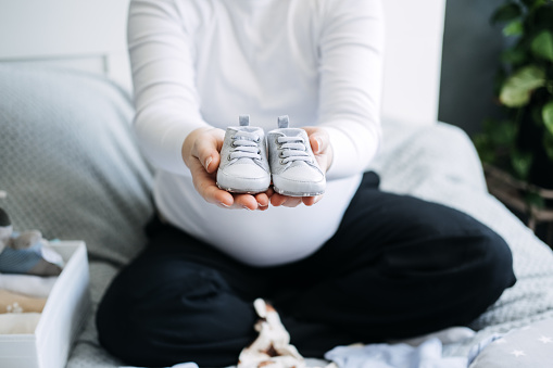 How to Organize Newborn Baby Clothes. Pregnant woman Using ornament boxes, baskets, or dividers to organize baby clothes in dresser drawers.