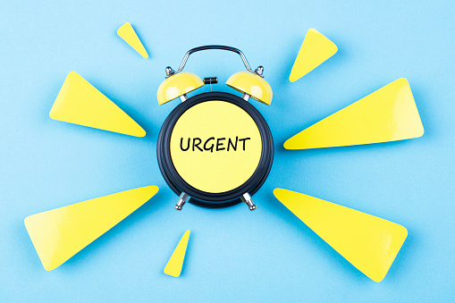 Alarm clock with word Urgent on blue background