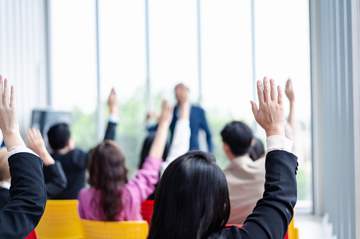 Business person raising hand during seminar. Hand up in conference asking to answer a question in business meeting room and seminar class.