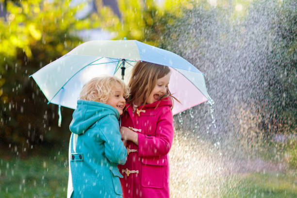istock Kids with umbrella playing in autumn shower rain. 1621168208