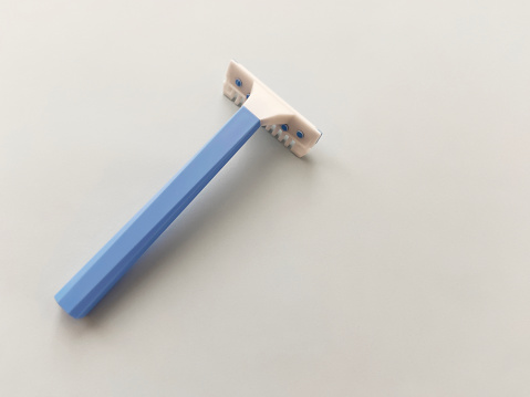 Plastic razor blade for care on blue background with copy space. Blue shaver