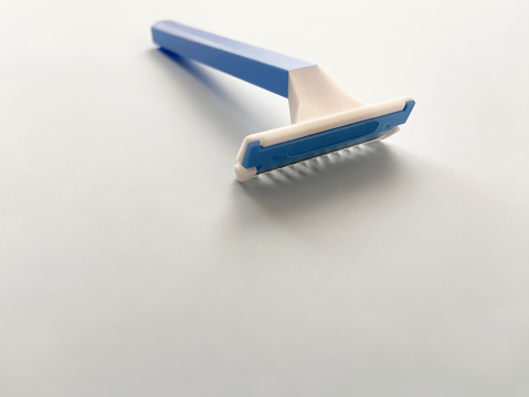 Plastic razor blade for care on blue background with copy space. Blue shaver