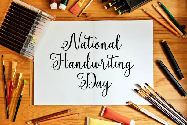 istock National Handwriting Day, 23 january. Hand lettering inscription text on paper notepad with pens and pencils on the table 1621176295