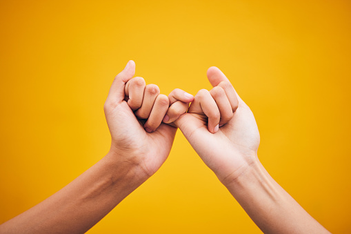 People, hands and pinky promise in studio with trust, help or hope for reconciliation on yellow background. Finger, emoji and deal by friends with secret, gesture and support expression or solidarity