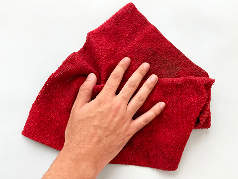 Hand holding dirty red microfiber cloth on the colored background