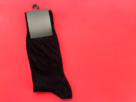 New black socks with empty label on the red background with copy space