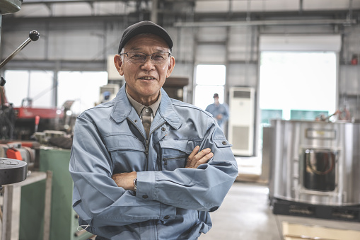 Senior Asian Industrial Worker Looking At Camera at factory.