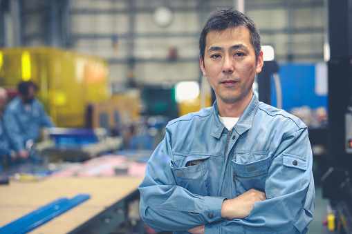 Asian Mature Male Industrial Worker Looking At Camera At Factory.
Professional Engineer Man arm crossed and confident.