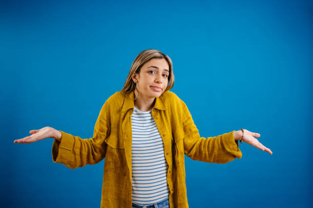 istock Young Woman Shrugging Her Shoulders While Standing Against A Blue Background 1621205292
