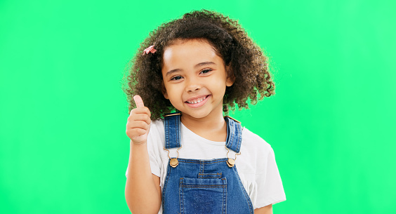 Happy, green screen and face of a child with a thumbs up isolated on a studio background. Winning, success and portrait of a girl kid with an emoji hand gesture for motivation, yes and agreement