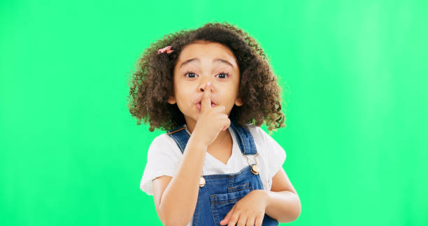 istock Face, green screen and child with finger on lips for quiet, silence or shush gesture on studio background. Noise, whisper and girl portrait with secret, emoji and hand symbol while posing isolated 1621208683