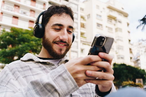 Mid adult man using mobile phone and listening music outdoors