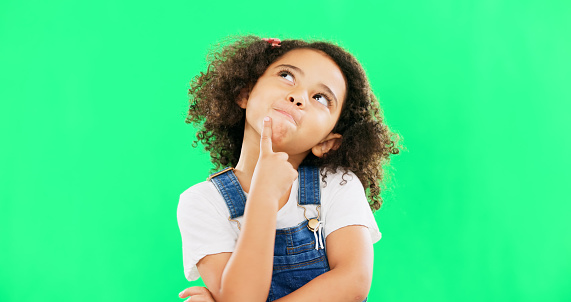 Thinking, green screen and a child with a decision isolated on a studio background. Doubt, think and a confused girl kid looking thoughtful, contemplating and planning an idea with mockup space