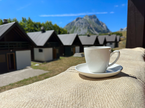 A white cup on the terrace with incredible view. Mountains, blu sky and small houses