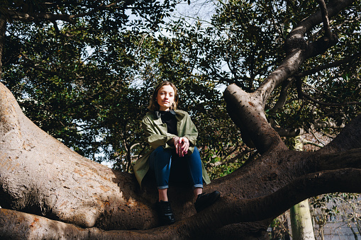 Portrait of a woman sitting on a tree trunk at the public park