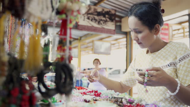 Asian woman choosing and buy hand made bracelets or bangle at accessories shop.