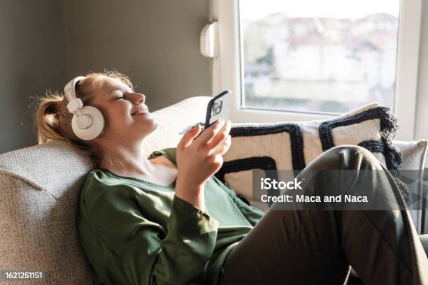 Young Woman Using Music Streaming Services On Her Phone Stock Photo - Download Image Now