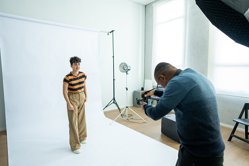 Photographer taking photos of a young model woman at studio