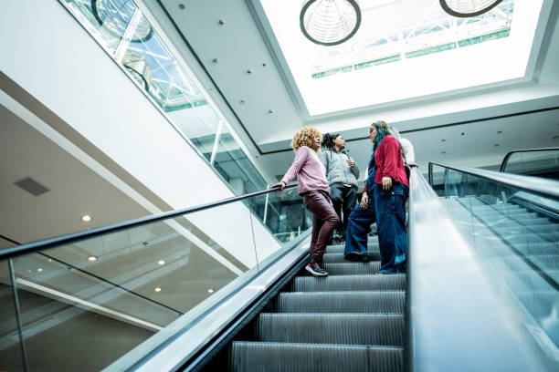 istock Young businesswomen talking while move down on an escalator at shopping mall 1621304322