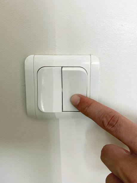 istock Turning on or off electric light switch. Finger pushing electric light switch push button on the wall 1621304856