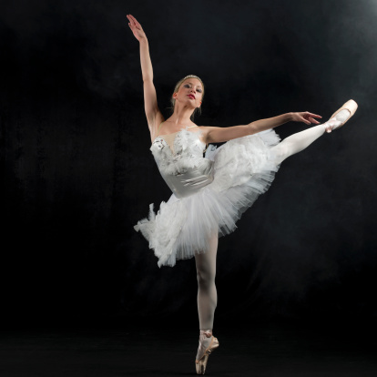 attractive ballerina poses gracefully in the studio on a black background