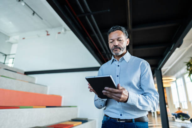istock Mature businessman using digital tablet and walking at office 1621319459