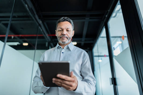 istock Mature businessman using digital tablet and walking at office 1621319465