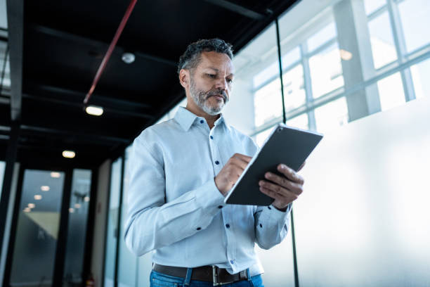 istock Mature businessman using digital tablet and walking at office 1621319470