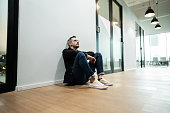 Worried businessman sitting on ground at office corridor