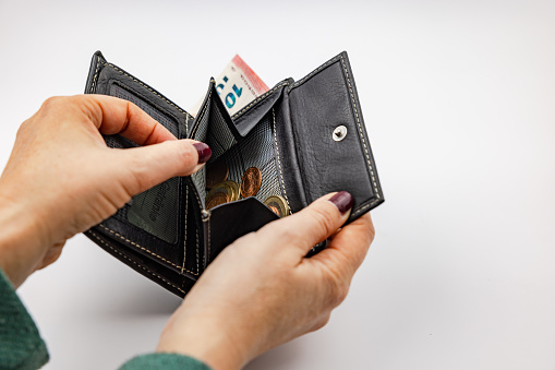 Macro image as a woman takes Euro banknotes from a leather wallet.