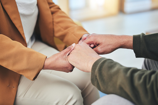 Support, mental health and patient holding hands with therapist in counseling session for depression, anxiety or trauma. Person, talking and psychologist listening with empathy, kindness or helping