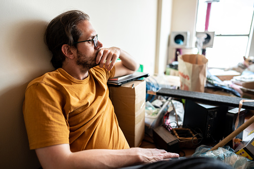 Worried adult man sitting on ground at home