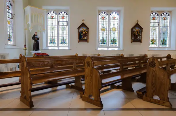 Pews, statue of St Francis of Assisi and stations of the cross in a Roman Catholic church