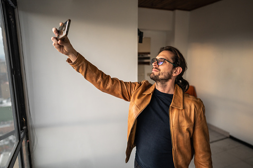 Mid adult man taking a selfie or filming at his new apartment
